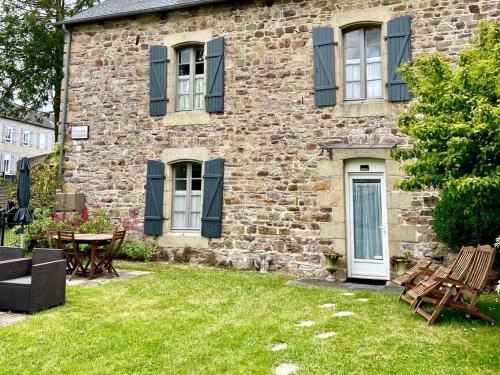 a brick house with blue shuttered windows and a yard at Chambres De St Michel in Paimpol
