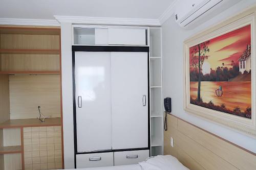 ein Schlafzimmer mit einem weißen Schrank und einem Gemälde an der Wand in der Unterkunft diRoma Rio Quente 1km do Hot Park in Rio Quente