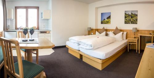 a bedroom with a bed and a table and a kitchen at Hotel Montfort in Sankt Anton am Arlberg