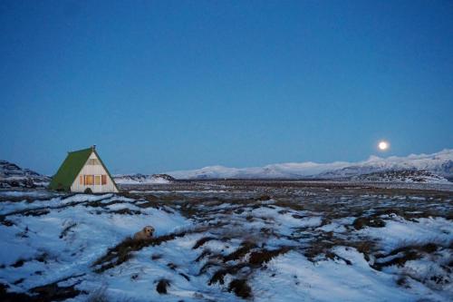 a barn in a snowy field with the moon in the background at Hömluholt Holiday Homes in Hömluholt
