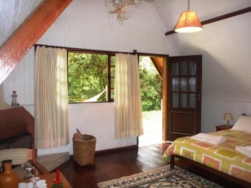 Un dormitorio con una cama y una ventana grande. en Pousada Passaredo, en Gonçalves
