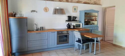 a kitchen with blue cabinets and a sink and a table at Bastide Saint Jean Baptiste in Baudinard