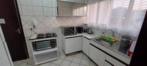 a small kitchen with a sink and a microwave at Apto 201 Parque Via Verde - Mobiliado 2 quartos in Jaraguá do Sul