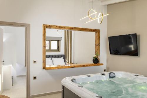 a bathroom with a tub and a tv and a mirror at Beachfront luxury suite in Kalyves