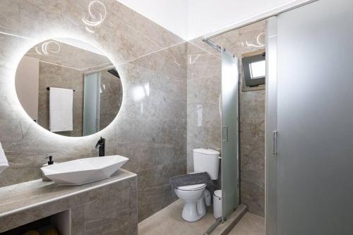 a bathroom with a sink and a toilet and a mirror at Beachfront luxury suite in Kalyves