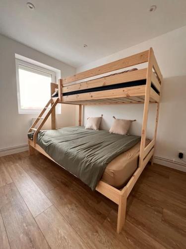 Ce lit superposé en bois se trouve dans un dortoir doté d'une fenêtre. dans l'établissement Stella résidence face à la mer, à Cucq