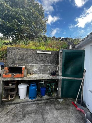 a garage with a green door and some buckets at Comfortable house with sea view in São Roque do Pico in São Roque do Pico