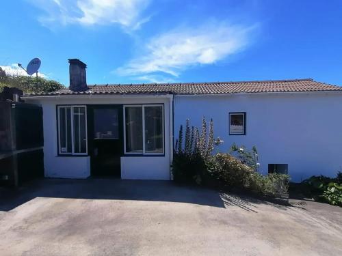 a white house with a driveway at Comfortable house with sea view in São Roque do Pico in São Roque do Pico