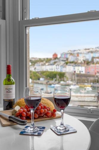 two glasses of red wine on a table with a window at Limpet Cottage - Beautiful Space & Close To Town in Brixham