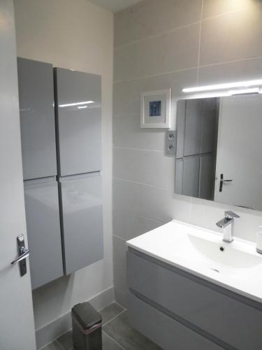 une salle de bain blanche avec un lavabo et un miroir dans l'établissement La Courtine, centre historique Narbonne, à Narbonne