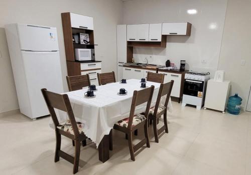 uma cozinha com uma mesa com cadeiras e uma geladeira em Apartamento Novo Próximo a pontos turisticos em Foz do Iguaçu
