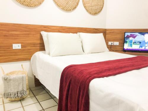 a bedroom with a bed with a red blanket on it at T-36: Flat charmoso a Beira mar da Pajuçara in Maceió
