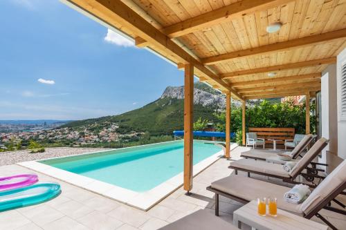 a villa with a swimming pool and a wooden ceiling at Barefoot Summer House in Klis