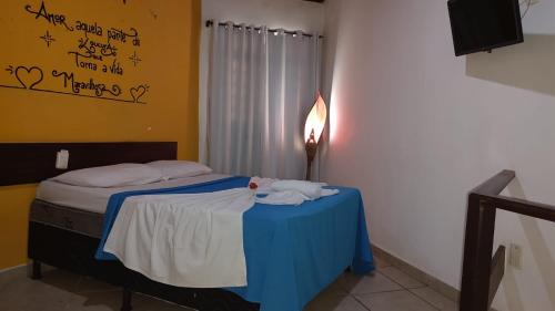 a bed with a blue table in a room with writing on the wall at Pousada Prime Center in Pipa