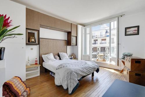 une chambre avec un lit et une grande fenêtre dans l'établissement Bel Appartement 96m2 16eme, à Paris