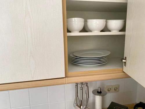 a kitchen cabinet with plates and bowls in it at Stilvolles Apartment mit Balkon, Küche & Parkplatz - Waldstetten Zentrum in Waldstetten