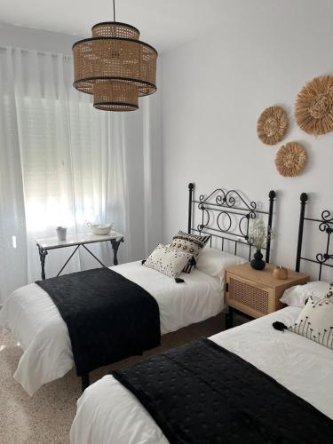a bedroom with two beds and a chandelier at Casa Gran Cinema in Sanlúcar de Barrameda