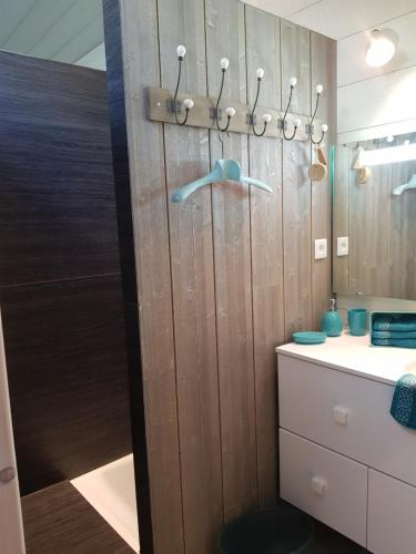 une salle de bain avec un mur en bois avec un lavabo et un miroir dans l'établissement La mercerie des bout's, à Houssay