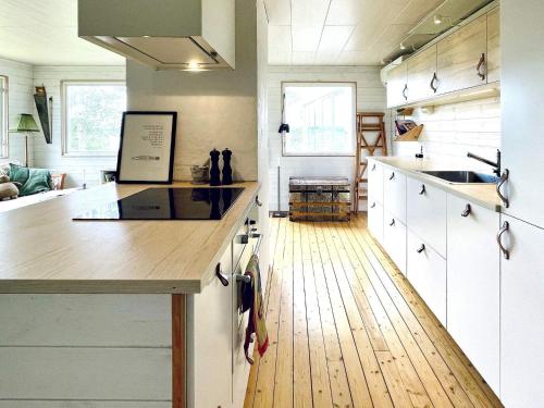 a kitchen with white cabinets and a wooden floor at 4 star holiday home in Uddevalla in Uddevalla