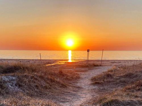 a sunset on a beach with the sun setting over the ocean at Welcoming cottage near the sea-By Traum in Mellbystrand