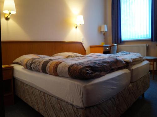a bed in a hotel room with a blanket on it at Landhotel Wilhelm Busch in Lüthorst
