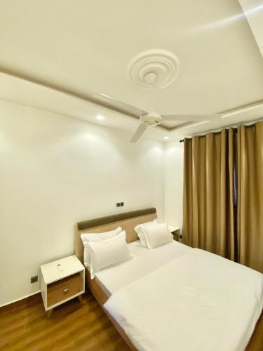 a bedroom with a white bed and a ceiling at RESIDENCE KARMA in Ouagadougou