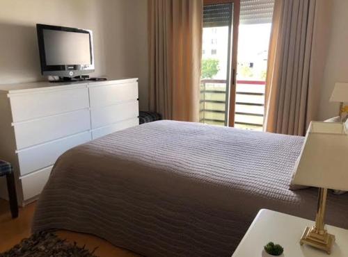 una camera da letto con un letto e una cassettiera con una TV sopra di Guia Cascais Room Suite Opportunity a Cascais