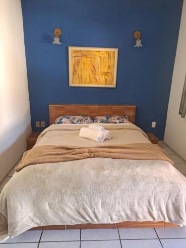 a bedroom with a large bed with a blue wall at Pousada Luar de Penedo in Penedo