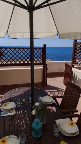 a table with plates and flowers and an umbrella at Casa vacanze con terrazza panoramica vista mare in Portu Maga