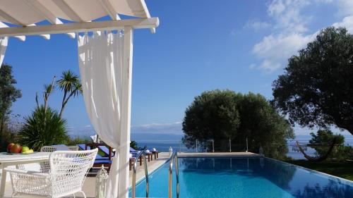 a swimming pool with a pergola and chairs next to it at Kappa Resort in Paliouri