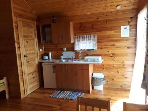 a kitchen in a log cabin with a sink at Drewniane Domki Pod Sokołem in Sterławki Wielkie
