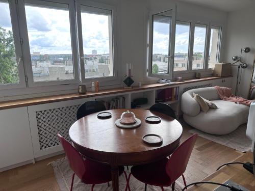 un salon avec une table, des chaises et des fenêtres dans l'établissement Magnifique 3 pièces à Aubervilliers, à Aubervilliers