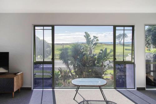 Una sala de estar con una mesa y una gran ventana. en Oceanview on Malibu, en Papamoa