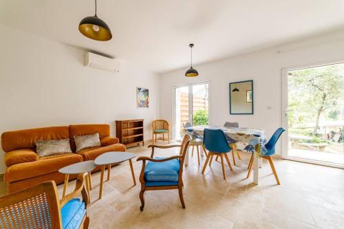 un salon avec un canapé, une table et des chaises dans l'établissement Rez-de-villa avec espace arboré privatif, à Sainte-Maxime