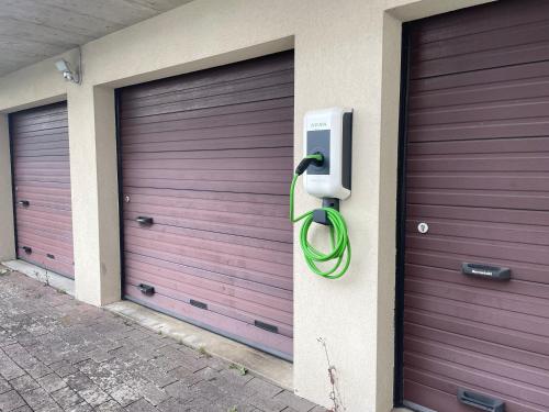 three garage doors with a green hose attached to them at Winner Star RVSVN Ferien Wohnung in Safenwil
