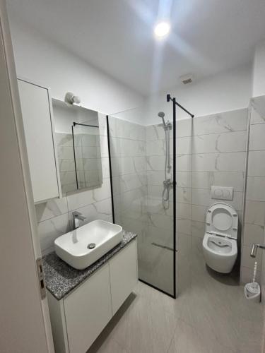 a white bathroom with a sink and a toilet at Sol Apartments in Lezhë