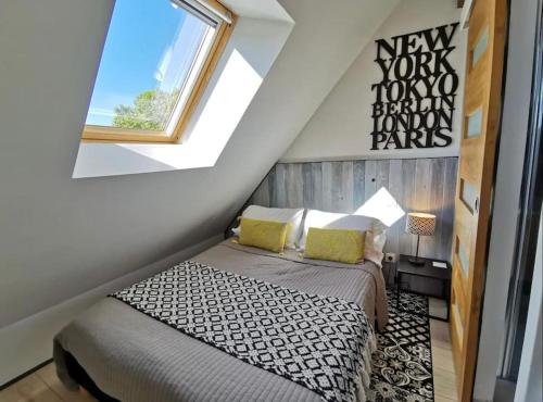 a bedroom with a bed in a attic with a window at ADORABLE PETIT LOFT CLIM WIFI au pied de la cité in Sarlat-la-Canéda
