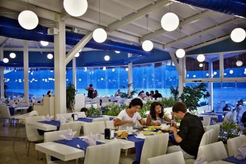 un grupo de personas sentadas en mesas en un restaurante en Bodrum Holiday Resort & Spa, en Bodrum City