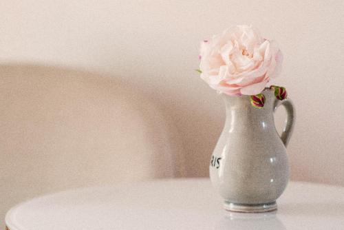 a white vase with a pink rose in it at Karnelund Krog & Rum in Simrishamn