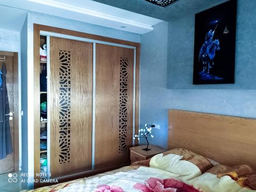 a bedroom with a bed and a wooden closet at Appartement à Bouznika prêt du plage Dahomey, plage bouznika, Bahia beach in Bouznika
