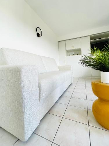 a white couch in a living room with a plant at Studio Square - zonrijke studio - zuidgericht balkon - dichtbij strand in Middelkerke