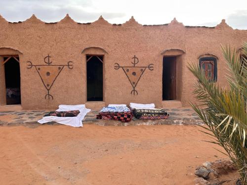 a building in the desert with a bunch of blankets at Auberge Dinosaur Kem Kem in Tafraoute Sidi Ali