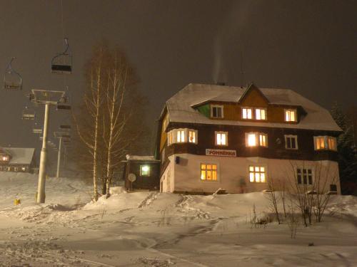 une grande maison dans la neige la nuit dans l'établissement Pomněnka, à Pec pod Sněžkou