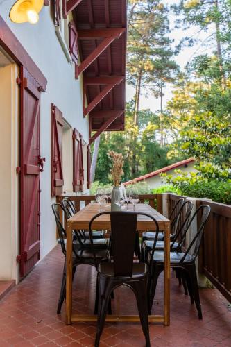 un patio avec une table et des chaises sur un balcon dans l'établissement Maison Landaise familiale 10 pers au cœur de la forêt, à Seignosse