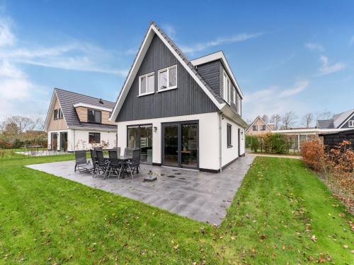 a white house with a black roof and a patio at Holiday Home in De Koog with Sauna and Garden in Westermient