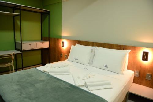 a bedroom with a bed with white sheets and green walls at Brisas Flat Hotel in Cuiabá