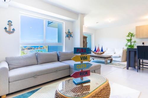 a living room with a couch and a table with pizza boxes at Deluxe Apt with Ocean View & Beach Access only 1 hour drive from San Jose in Puntarenas