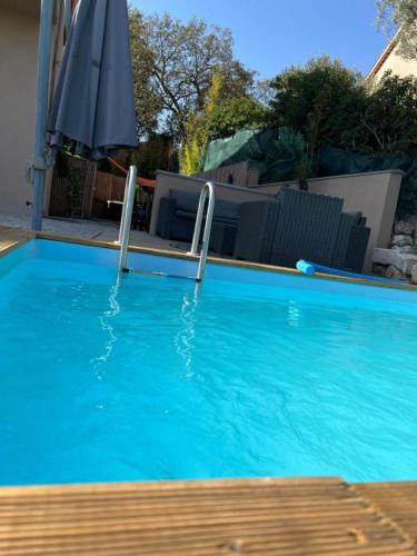 une grande piscine bleue avec un parasol dans l'établissement Magnifique T2 jacuzzi piscine, à Fréjus