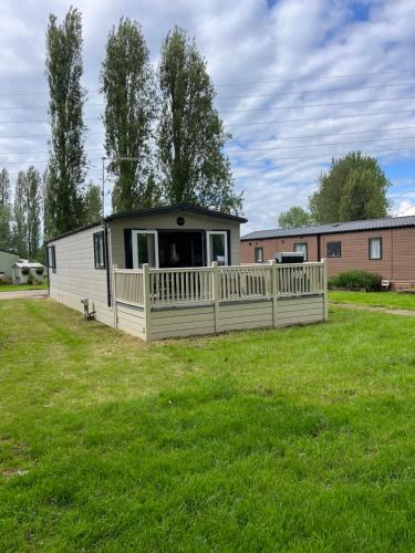 a mobile home with a porch on a grass field at family fun getaway holiday home in Northampton