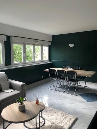 - un salon avec des murs verts, des tables et des chaises dans l'établissement Appartement - Vitry sur Seine, à Vitry-sur-Seine